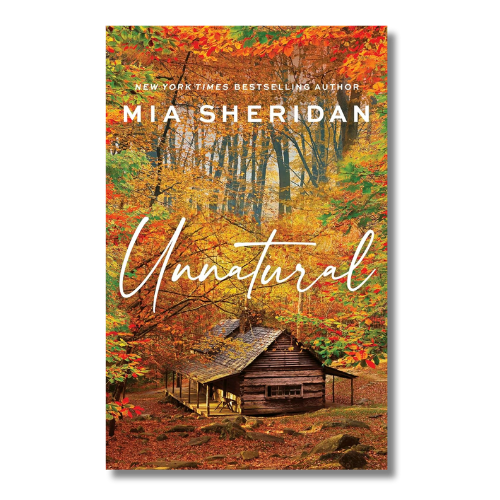 Book cover for 'Unnatural' by Mia Sheridan, featuring an autumn forest scene with colorful fall foliage and a rustic cabin, with the title in large white script across the center.